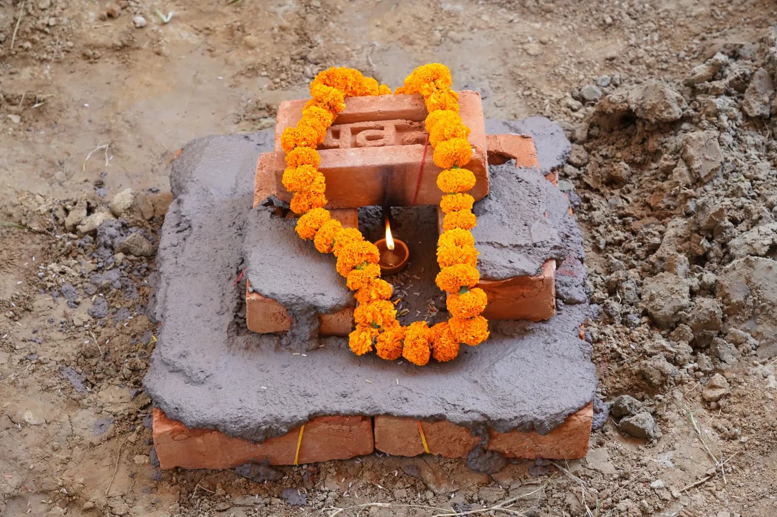 Ceremonial foundation brick garlanded with marigolds and lit with a diya during the Bhoomi Pujan for Maxvolt Energy's Aligarh battery manufacturing plant